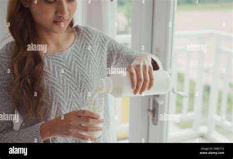 Young Woman Pouring Milk Into Glass Stock Photo Alamy