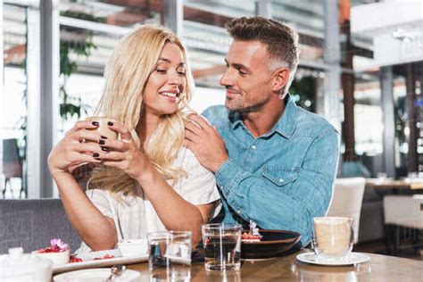 Boyfriend Hugging Smiling Girlfriend And She Holding Cup Of Coffee At