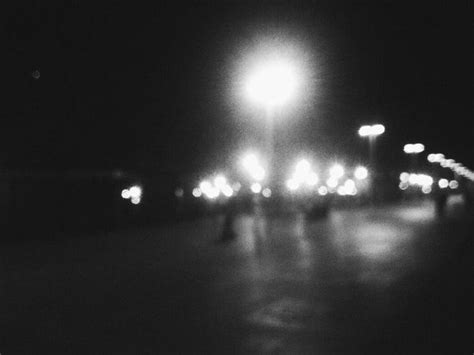 Black And White Photo Of People Walking Down The Street At Night With