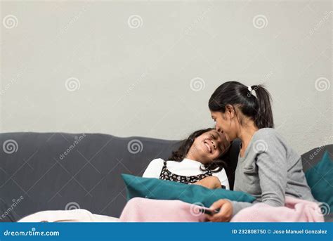 mother and daughter having fun together watching television at the sofa at home photography