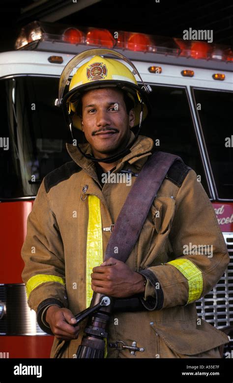 Portrait Of Male African American Firefighter Standing In Front Of Fire