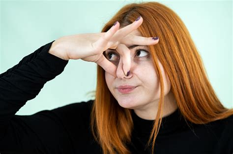 Funny Pretty Redhead Girl Showing Bad Smell Sign With Her Fingers Stock