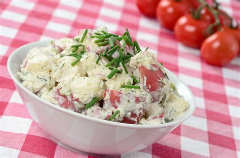 A White Bowl Filled With Potato Salad On Top Of A Checkered Table Cloth