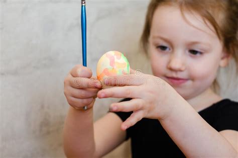 Little Girl Paints An Colored Easter Egg With A Brush Stock Photo