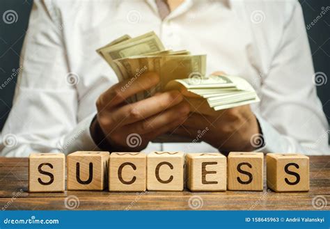 Wooden Blocks With The Word Success And Businessman With Money