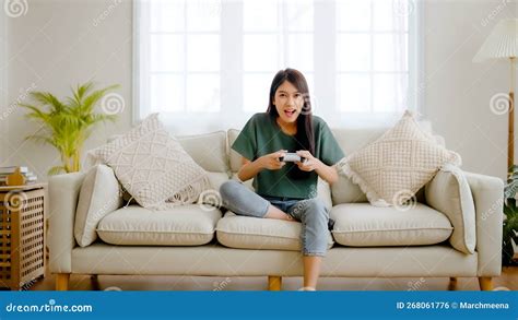 Beautiful Young Asian Woman Sitting On Sofa And Holding Joystick