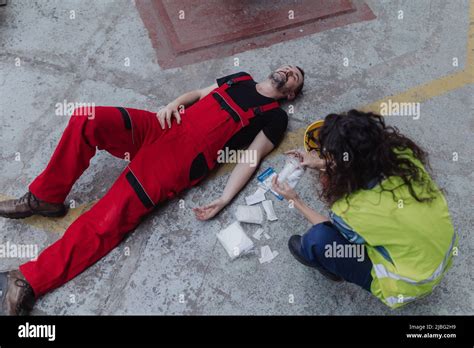 Woman Is Helping Her Colleague After Accident In Factory First Aid Support On Workplace Concept