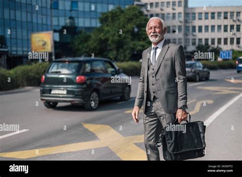 Smiling Elderly Businessman Carrying Laptop Bag While Hailing For Taxi