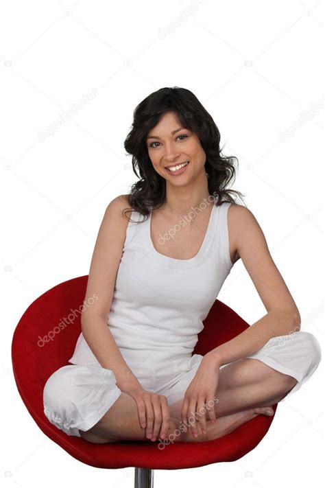 Woman In White Sitting Cross Legged In A Red Chair Stock Photo By