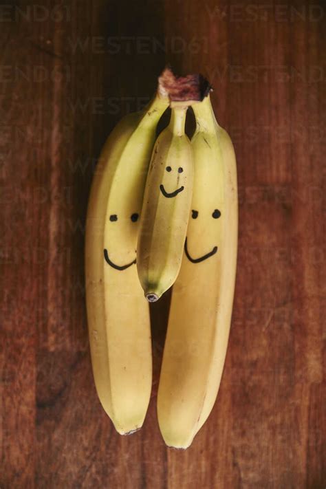 Bunch Of Two Large And One Small Bananas With Smiley Faces Stock Photo