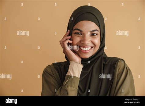 Black Muslim Woman In Hijab Smiling And Looking At Camera Isolated Over Beige Background Stock