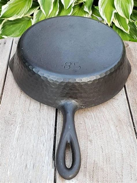 A Cast Iron Skillet Sitting On Top Of A Wooden Table Next To Green Plants