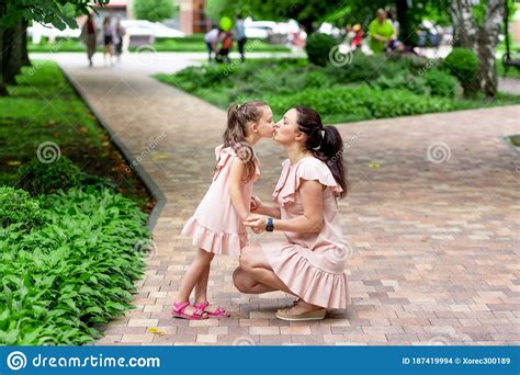 Happy Mother And Daughter 5 6 Years Old Walk In The Park In The Summer Mother Kisses Her