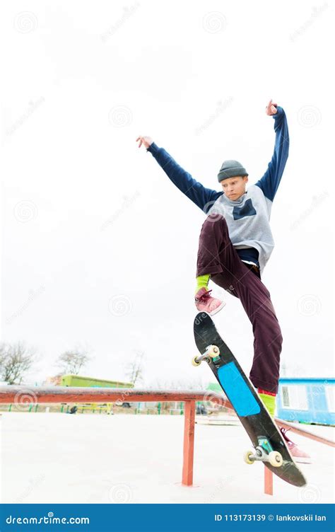 A Young Teenager A Skateboarder Does A Trick On The Railing In A