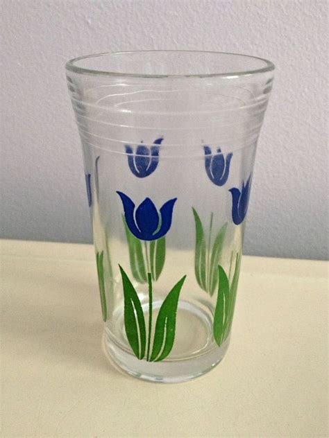 A Glass With Blue And Green Flowers Painted On The Inside Is Sitting On