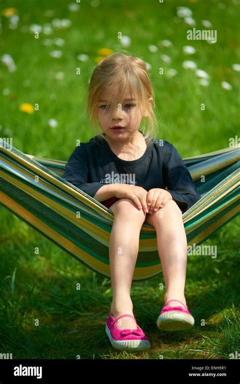 Portrait Of Little Child Blond Girl Lying And Resting In A Hammock