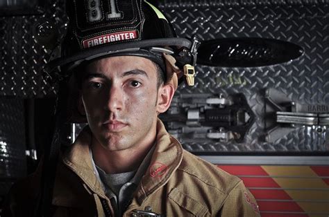 A Firefighter Standing In Front Of A Truck With His Helmet On And