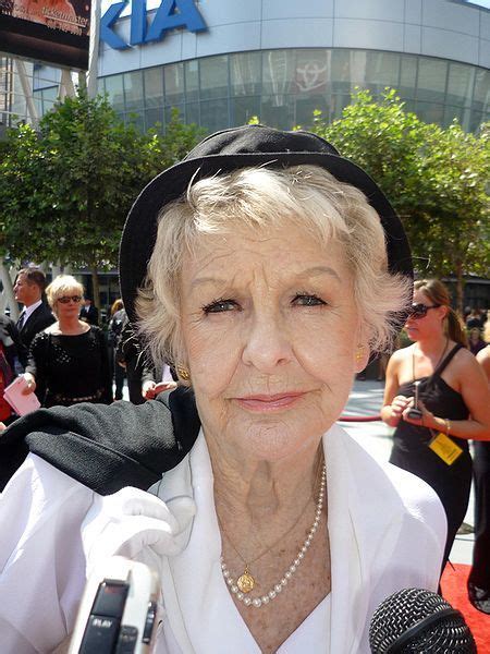 an older woman holding a microphone and wearing a black hat