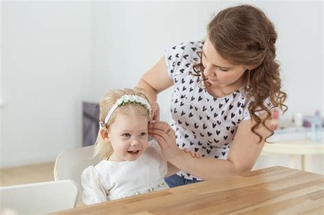 Mother Helps Her Deaf Baby Daughter Putting Hearing Aid In Little Girl