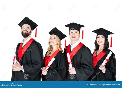 Students In Graduation Gowns And Mortarboards Holding Diplomas On White