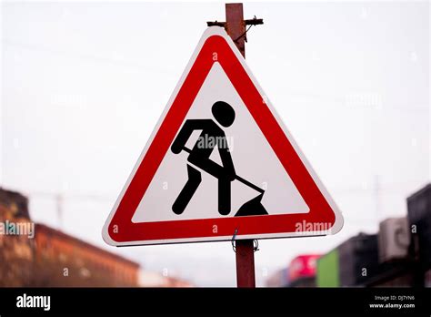 Red And Black Under Construction Sign With Digging Man In The Street