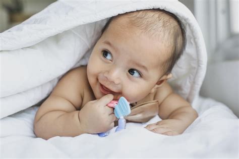 Premium Photo Sweet Baby Is Lying On The Bed And Biting Teether Under