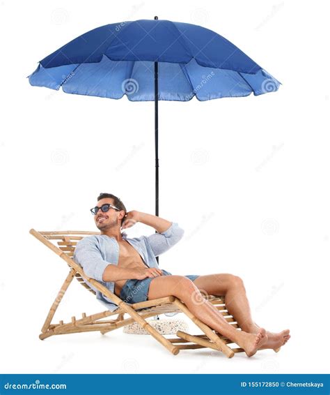 Young Man On Sun Lounger Under Umbrella Against White Beach