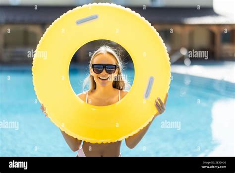 schöne frau im bikini mit einem aufblasbaren ring am pool und lächelnd frauen tragen bikini und