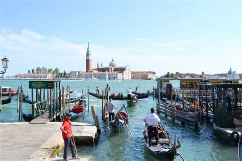 Venice Lagoon With A Queue Of Gondolas With Tourists Sitting In Them