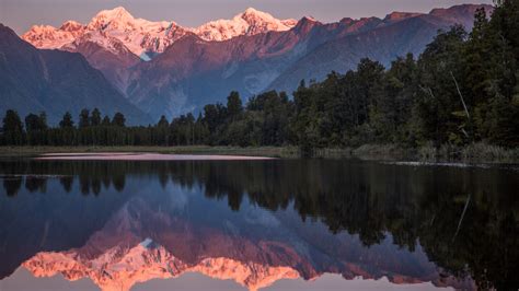 Snowcapped Mountains Cook And Fox Reflected In Lake Matheson At Sunset