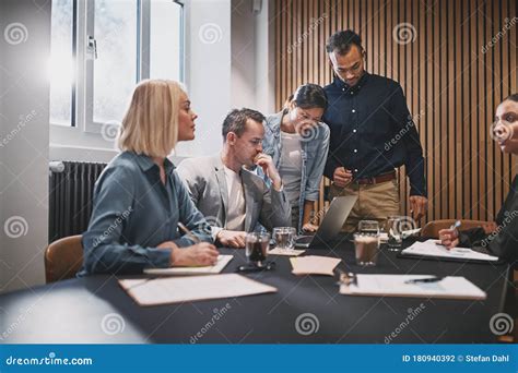 Businesspeople Working On A Laptop During A Boardroom Meeting Stock