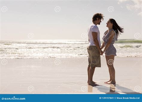 Romantic Young Couple Holding Hands And Looking Each Other On Beach