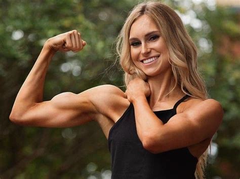 A Woman Flexing Her Muscles In Front Of Trees