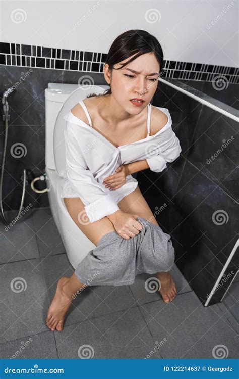 Woman Sitting On Toilet And Holding Her Painful Stomach Stock Image