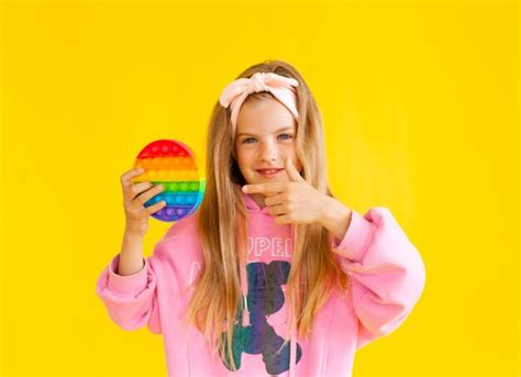 premium photo little blonde girl holding pop it antistress toy on yellow background with place