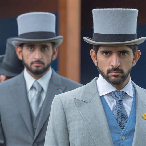 Two Men In Suits And Hats Standing Next To Each Other With One Man