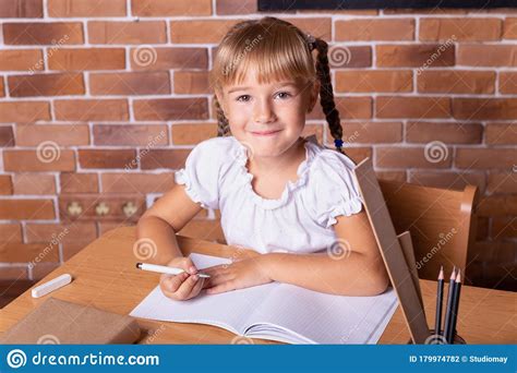 Smiling Student Girl Sitting At A School Desk And Studying Math The