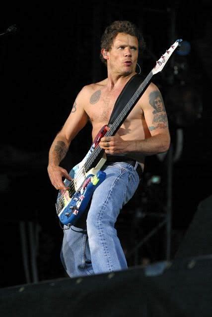 A Shirtless Man Playing An Electric Guitar On Stage