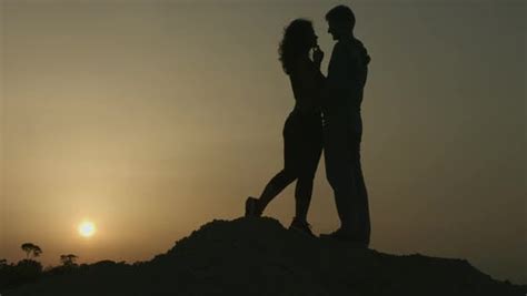 história romântica de duas pessoas apaixonadas silhueta de casal se beijando ao pôr do sol