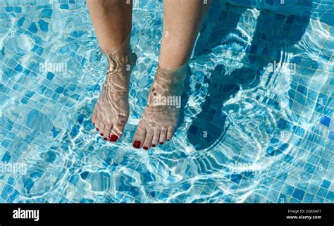 Womans Feet With Red Painted Nails Dipped In The Water Of A Swimming
