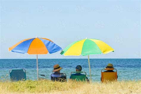 Image Of People Sitting In Beach Chairs Under Colourful Umbrellas
