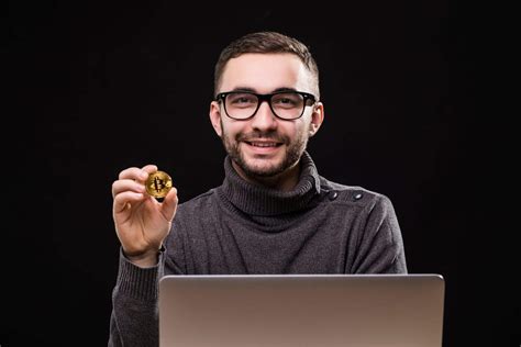 Portrait Of A Happy Businessman Showing Bitcoin While Sitting At Desk