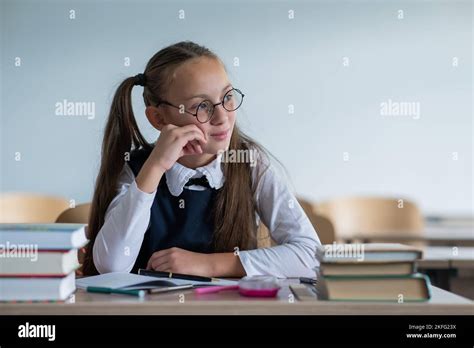 Caucasian Girl With Two Ponytails Wearing In Glasses Sits At A School