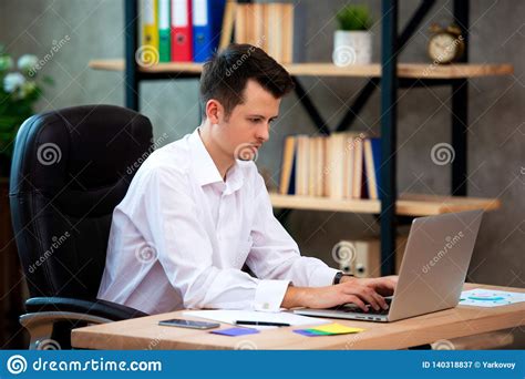 Concentrated Young Manager Man Sitting At Office Desk Working On Laptop