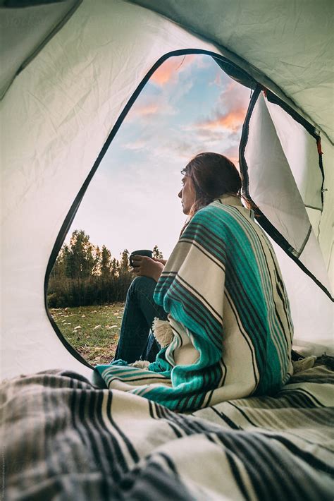 Female Camper Sitting At The Entrance To Her Tent With Coffee At Dawn By Stocksy Contributor