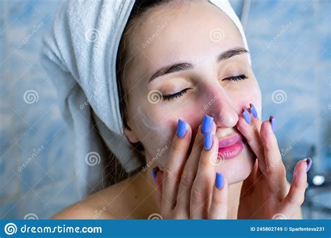 close up portrait of smiling brunette girl cleaning her cheeks with purifying foam isolated on