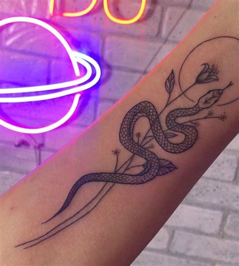 A Womans Arm With A Snake Tattoo On It And A Neon Sign In The Background