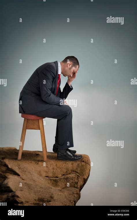 Depressed Businessman Suffering Depression On A Cliff Ledge Stock Photo