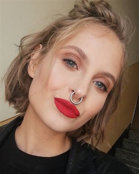 A Woman With Red Lipstick And A Nose Ring On Her Nose Is Looking At The Camera