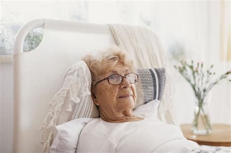Sick Senior Woman With Glasses Lying In Hospital Bed Stock Image